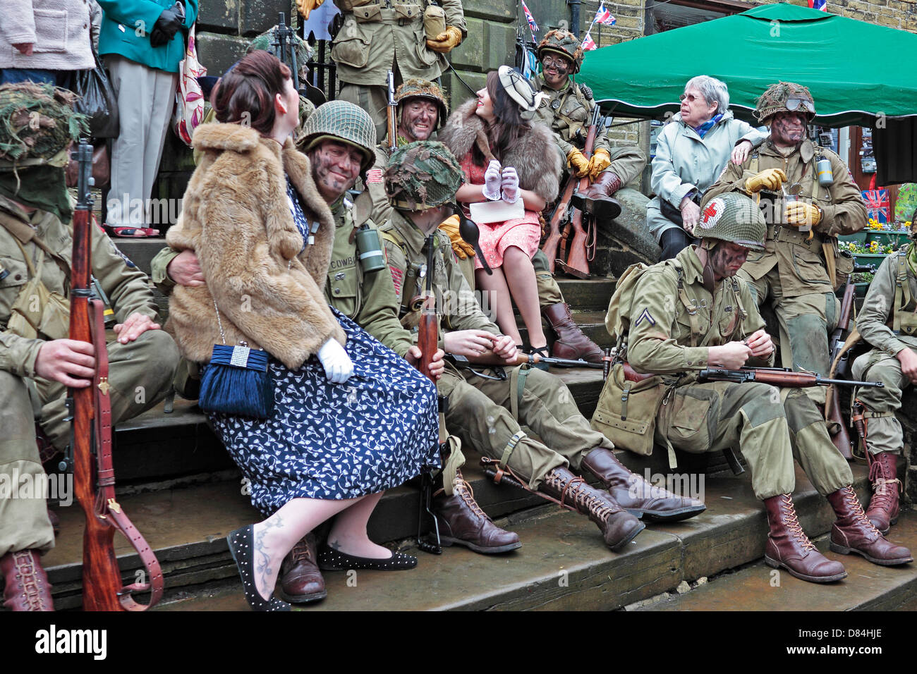 Haworth 40's Weekend GIs resto sui gradini della chiesa con ragazze locali Foto Stock