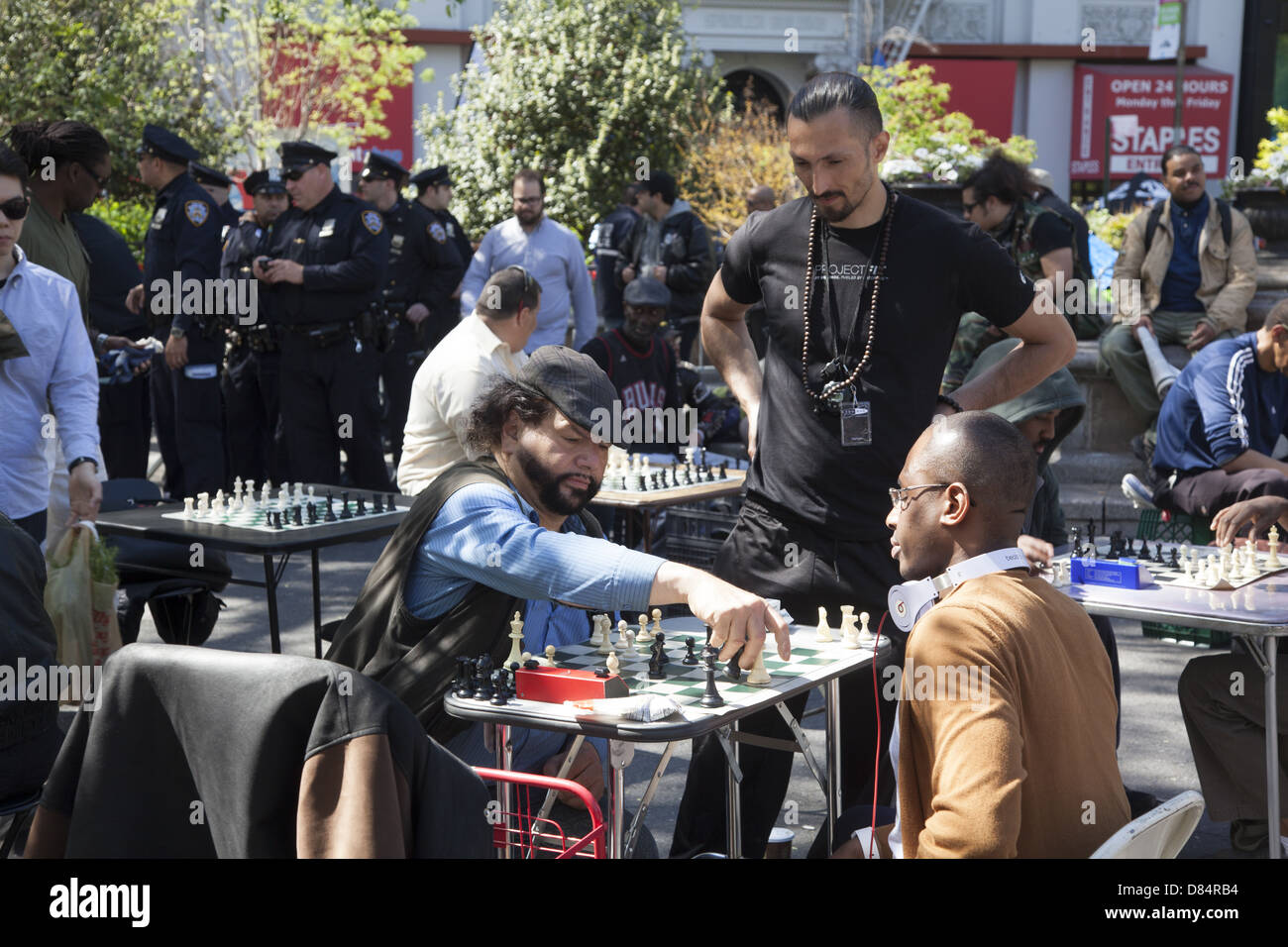 I giocatori di scacchi a Union Square; New York City; forte la presenza della polizia in background durante il giorno di maggio rally. Foto Stock