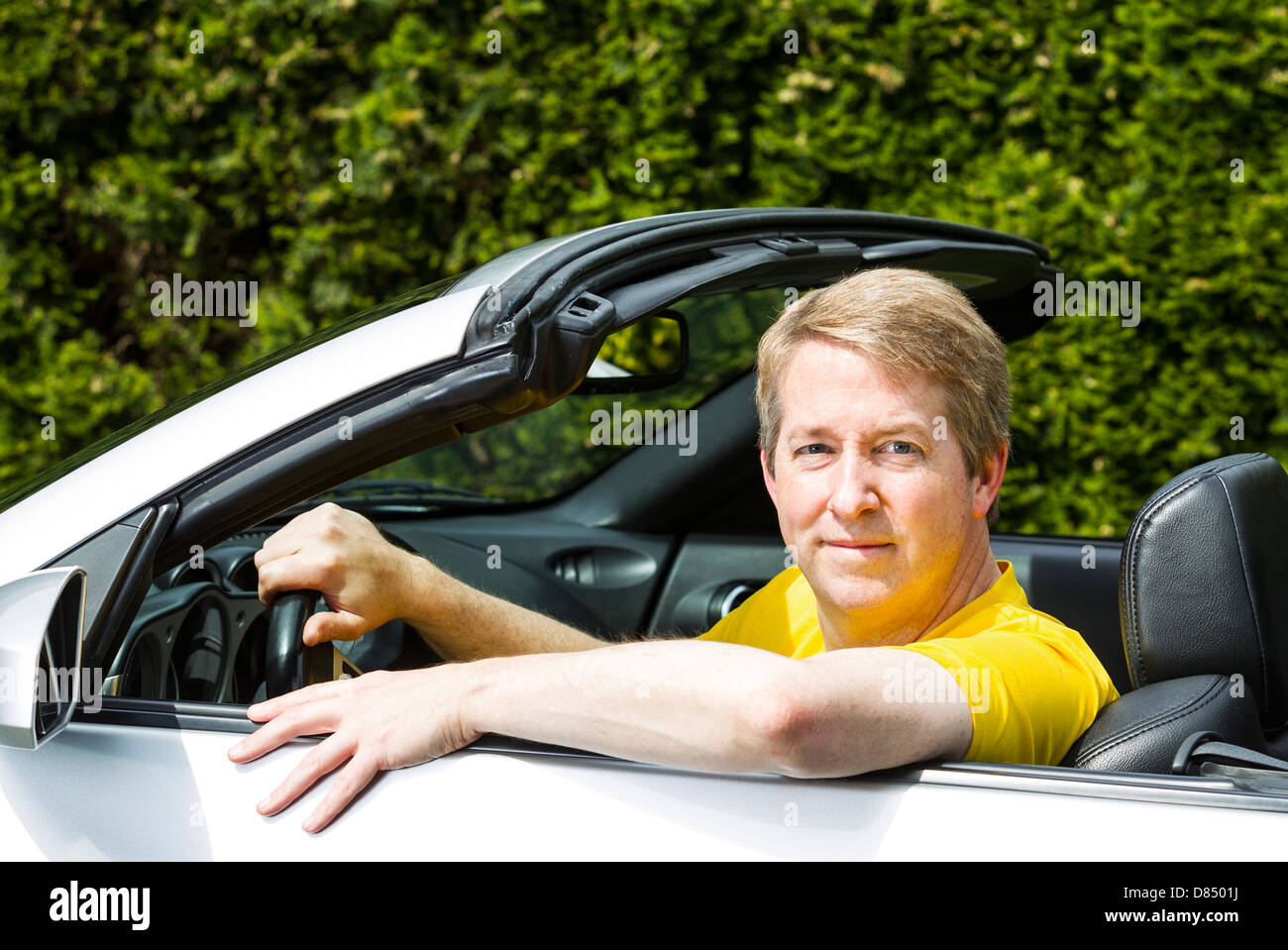 Uomo maturo cercando di agire raffreddare nella sua autovettura convertibile Foto Stock