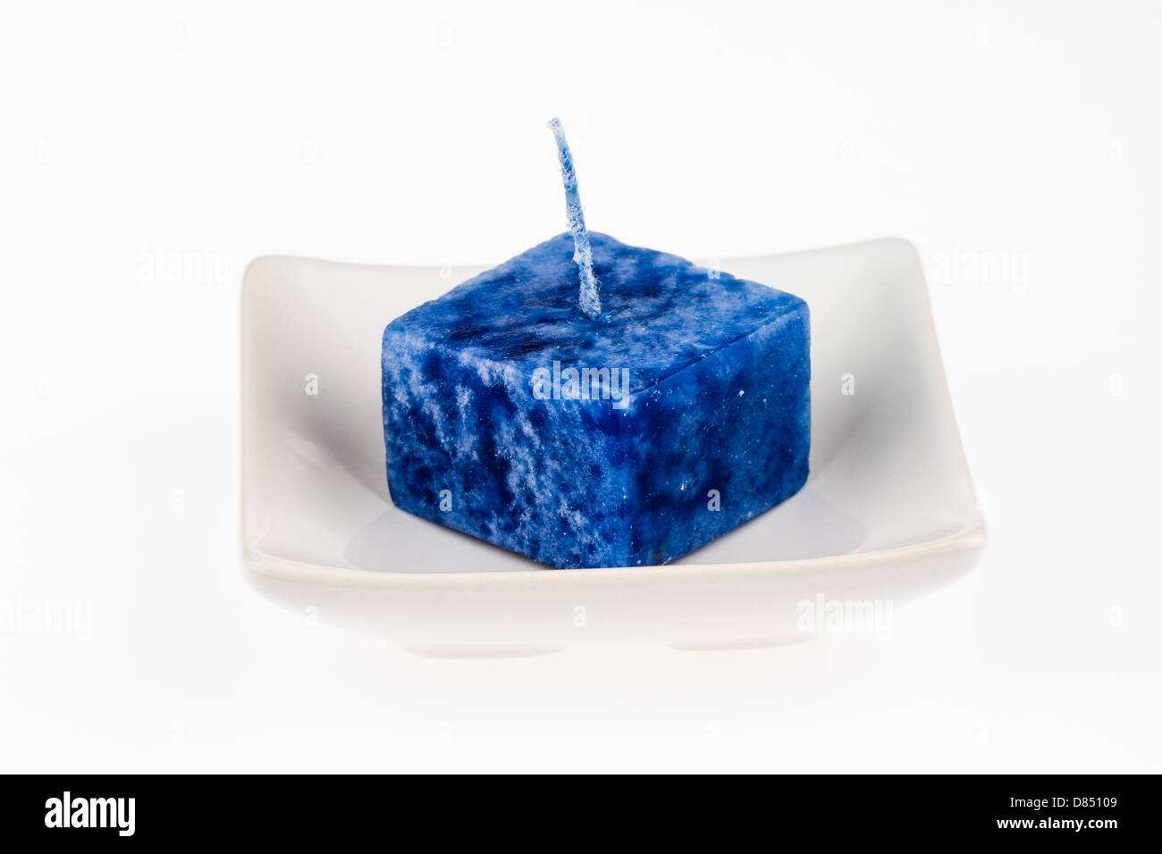Candela blu su una piastra isolata su uno sfondo bianco. Foto Stock