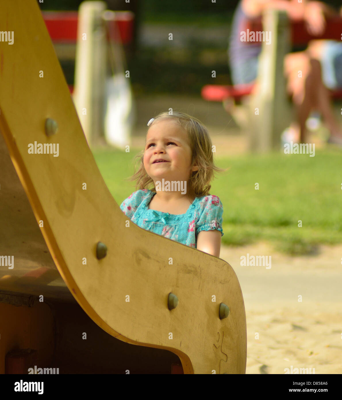 2 anno di età bambina guardando un grande scorrere sul parco giochi Foto Stock