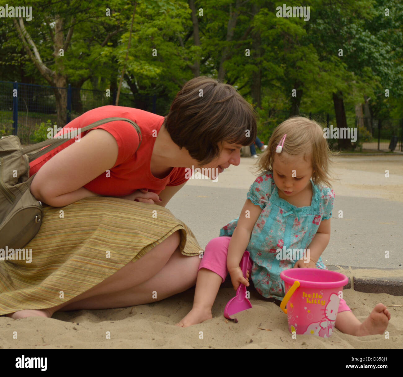 2 anno di età bambina con la madre nella buca di sabbia a giocare giochi Parco giochi Foto Stock