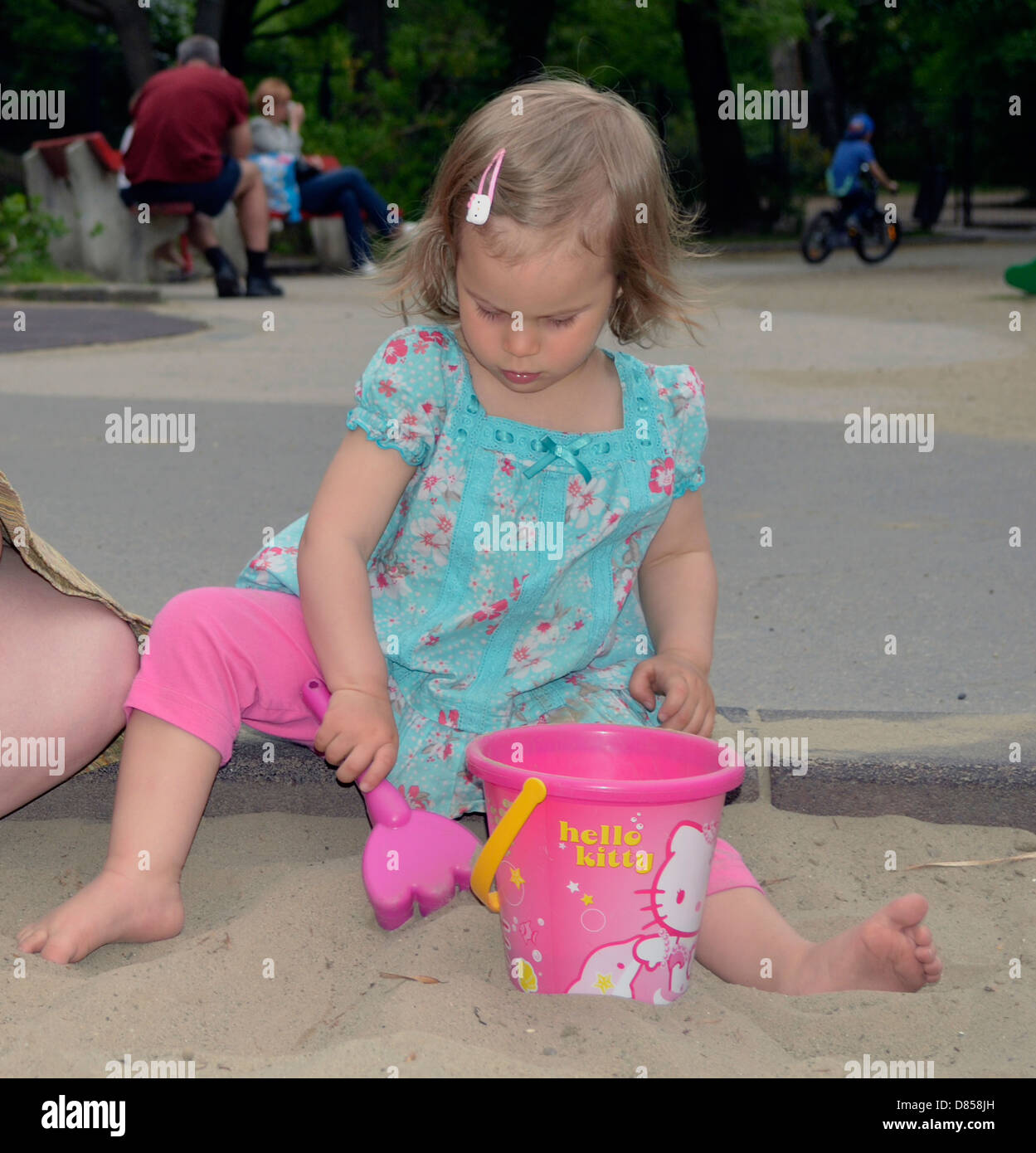 Bambina giocando in sabbia al parco giochi secchio di riempimento con sabbia Foto Stock