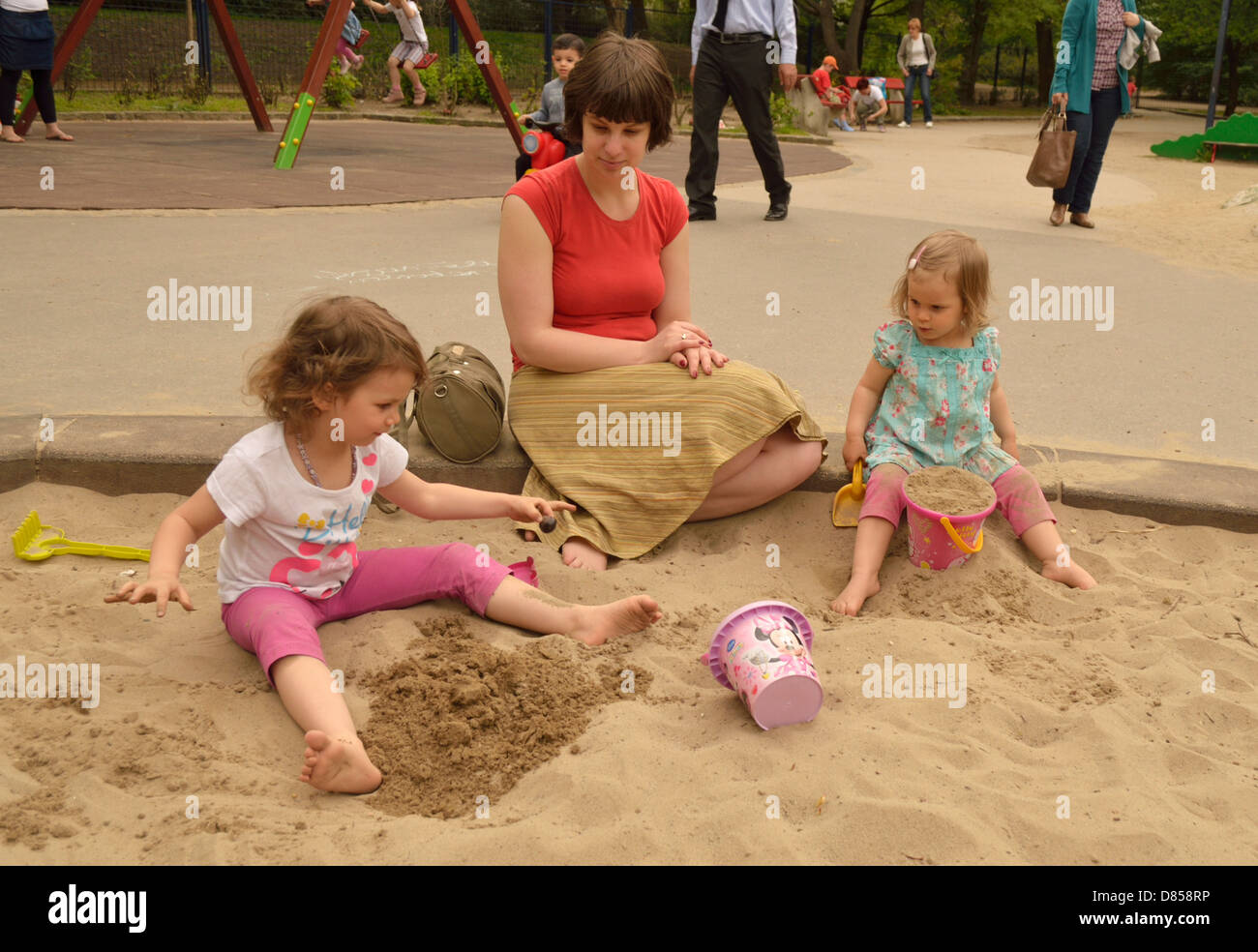 2 e 4 anno vecchio bambine con la madre nella buca di sabbia a giocare giochi Parco giochi Foto Stock