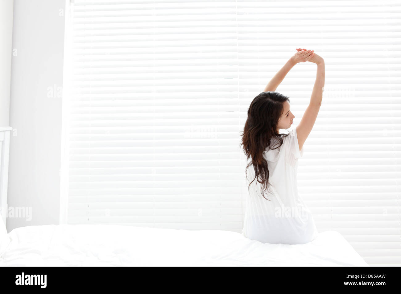 Giovane donna seduta sul letto di stretching. Foto Stock