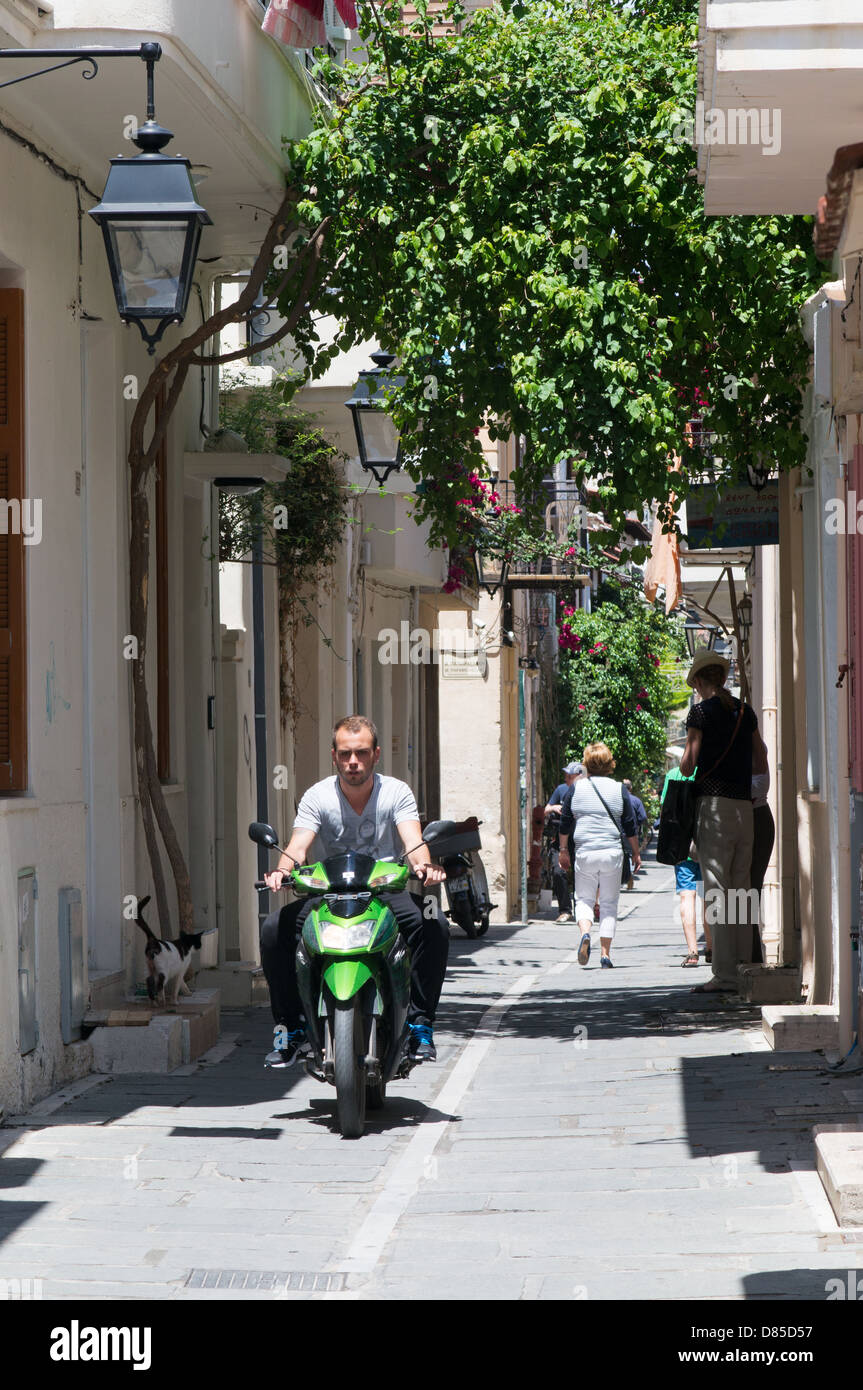 Un motociclista aziona verso il basso di uno stretto vicolo all'interno di Rethimno città vecchia, Creta Foto Stock