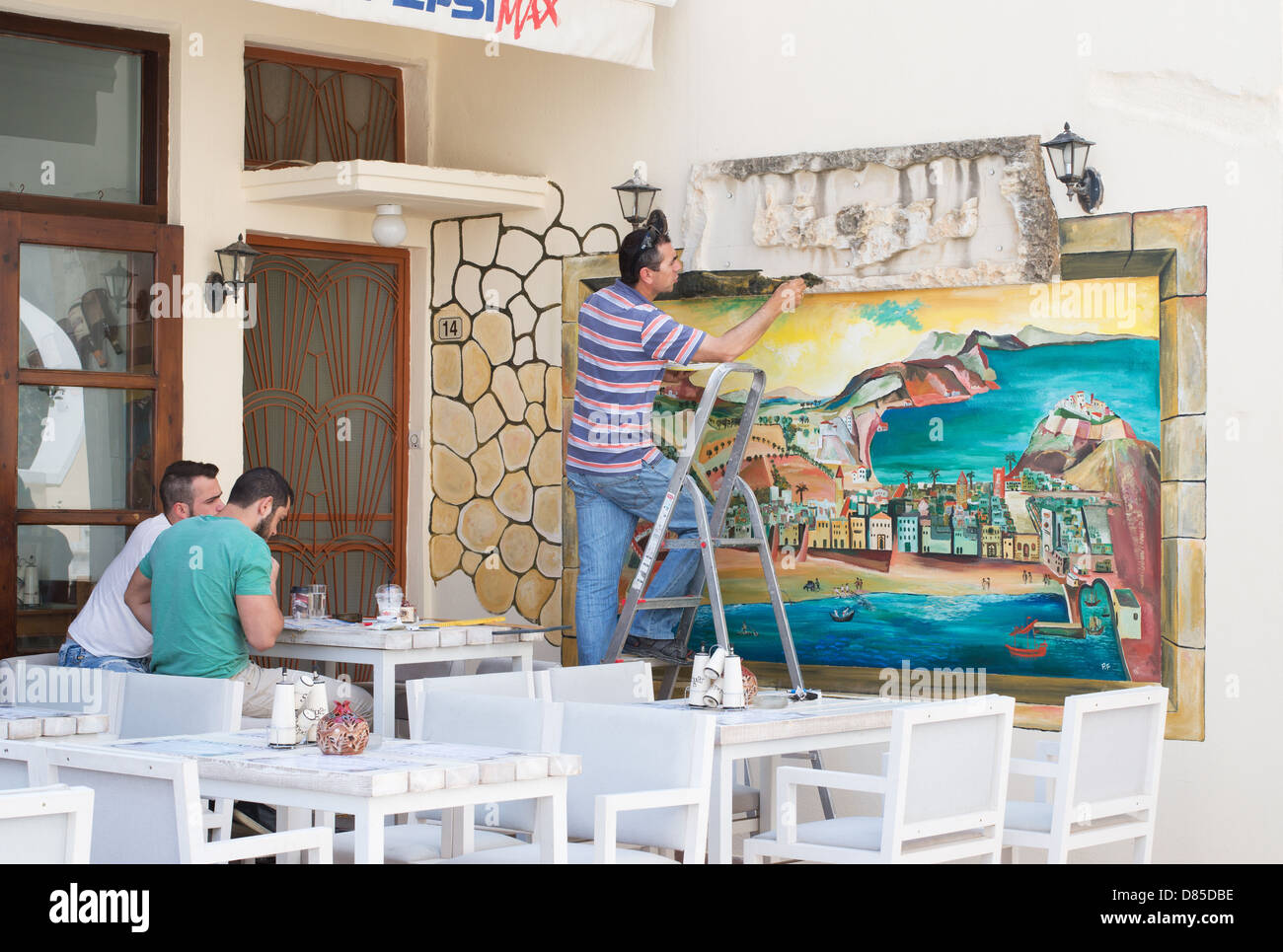 Artista pittura murale presso una caffetteria all'interno di RETHIMNO, CRETA Foto Stock