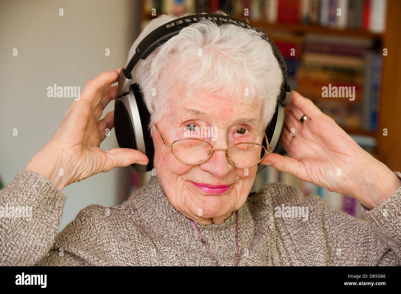 Un'anziana donna che indossa orecchio esterno cuffie Foto Stock