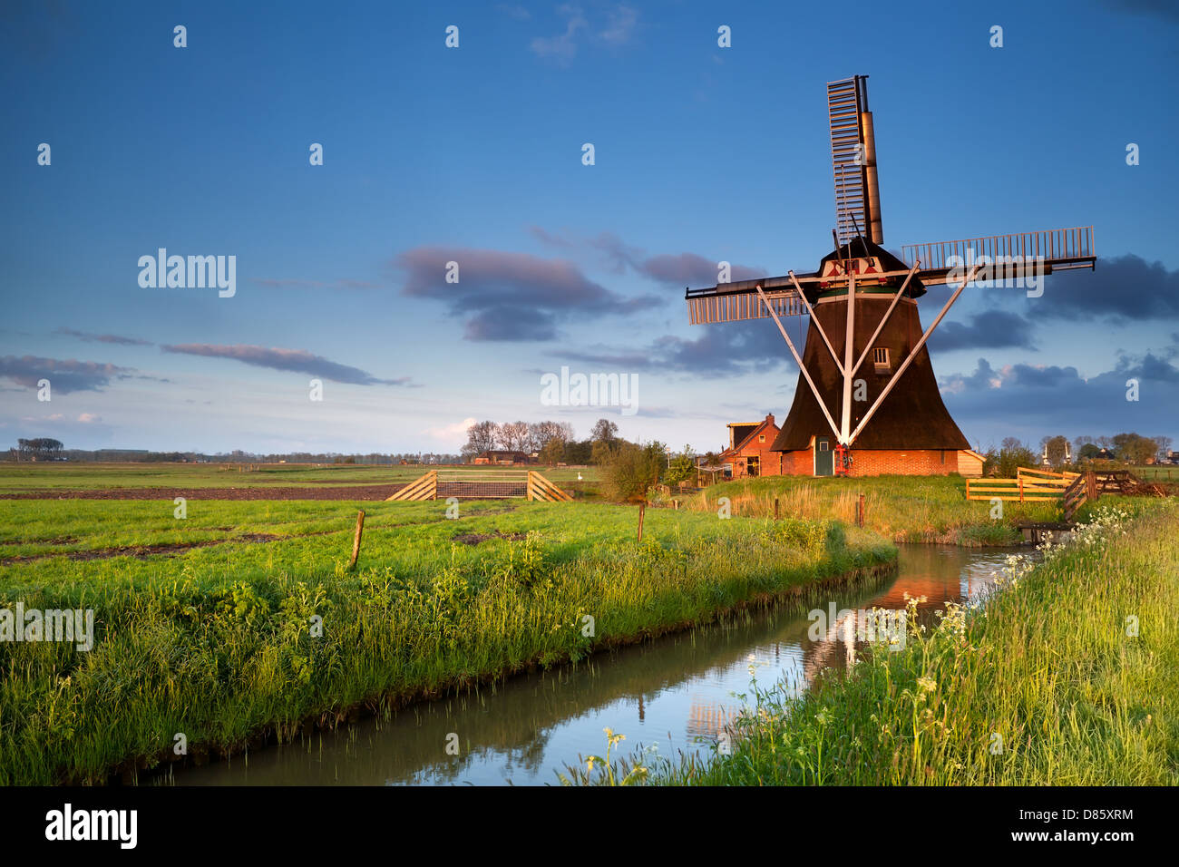Mulino a vento olandese si riflette nel fiume in alba la luce solare, Olanda Foto Stock