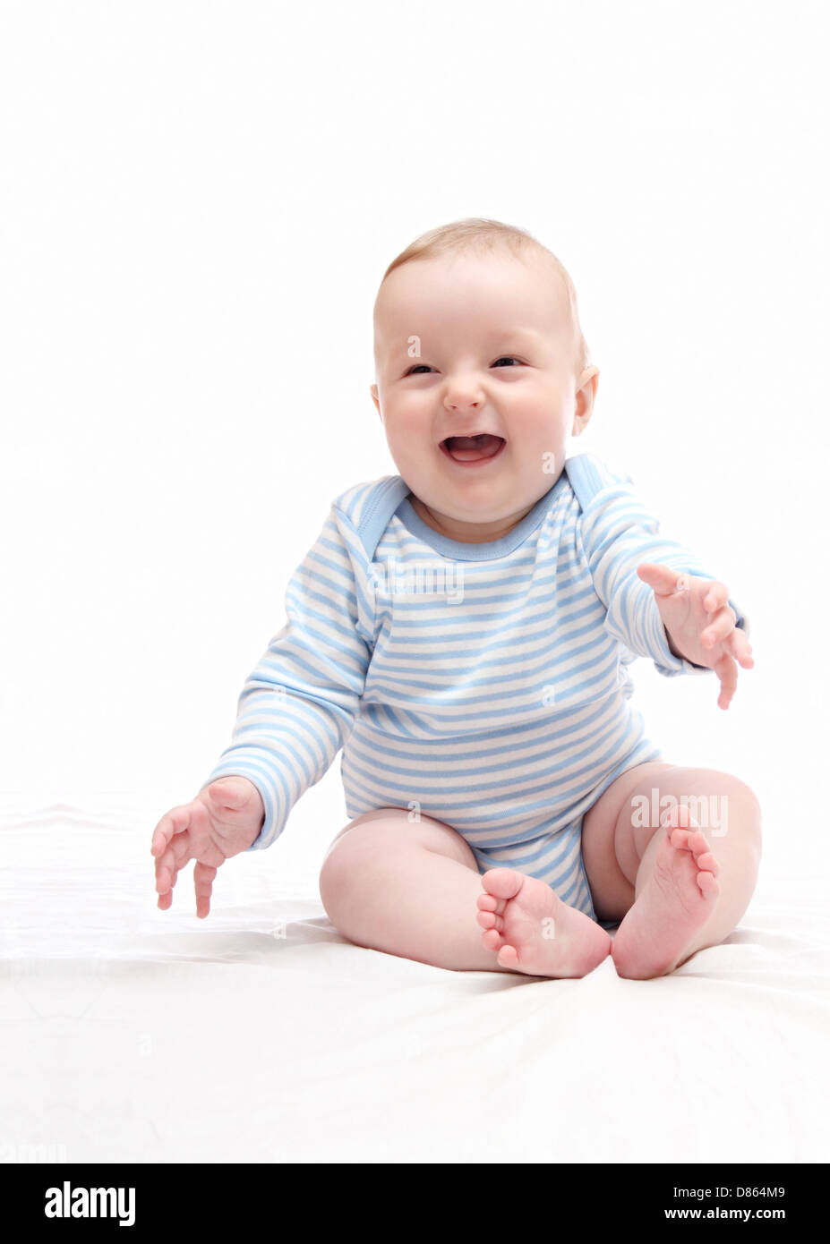 Bella ridere happy baby boy seduta sul letto bianco Foto Stock