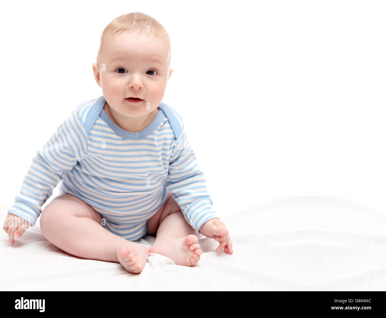 Bambino seduto sul letto bianco Foto Stock
