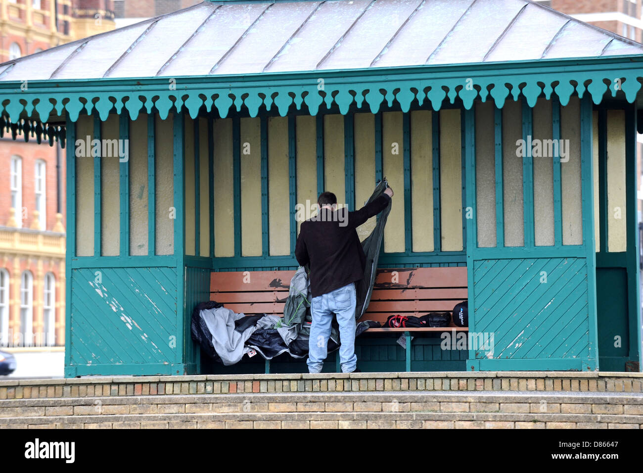 L'uomo chiarisce il suo sacco a pelo dormire dopo ruvida in un rifugio sul lungomare Hove Regno Unito Foto Stock