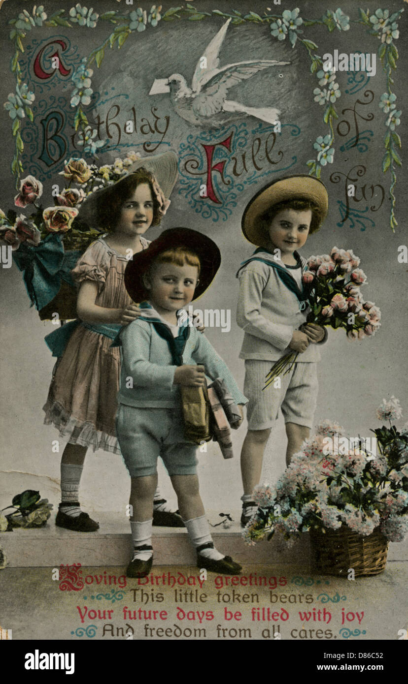 Tre bambini che portano fiori di compleanno Foto Stock