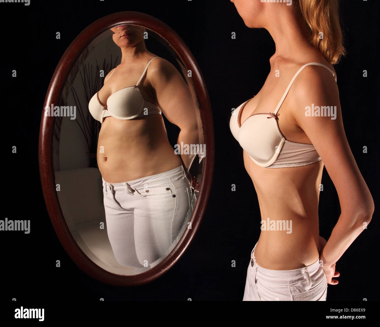 Skinny donna vedendosi grasso in uno specchio Foto Stock