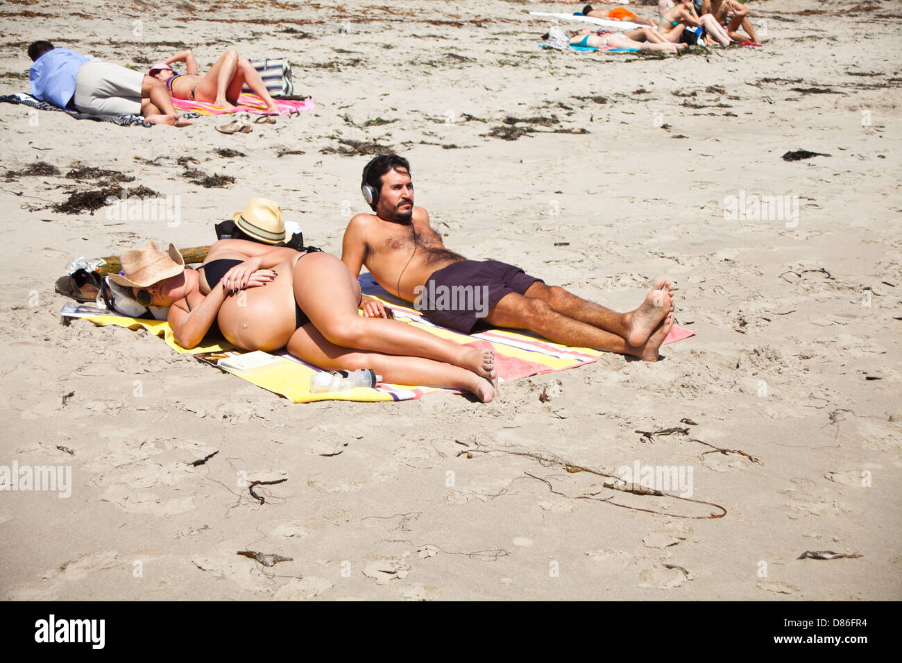 Un aspetta incinta giovane posa sulla spiaggia Foto Stock
