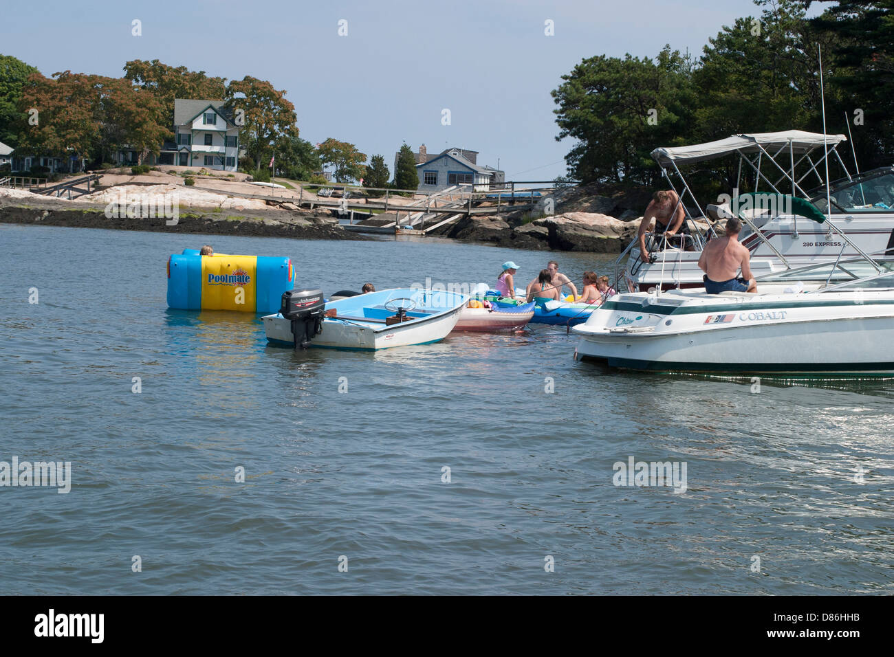 I barcaioli sgradito ancora vicino a costosi case sull'isola rocciosa costa in Long Island Sound, Connecticut USA. Foto Stock