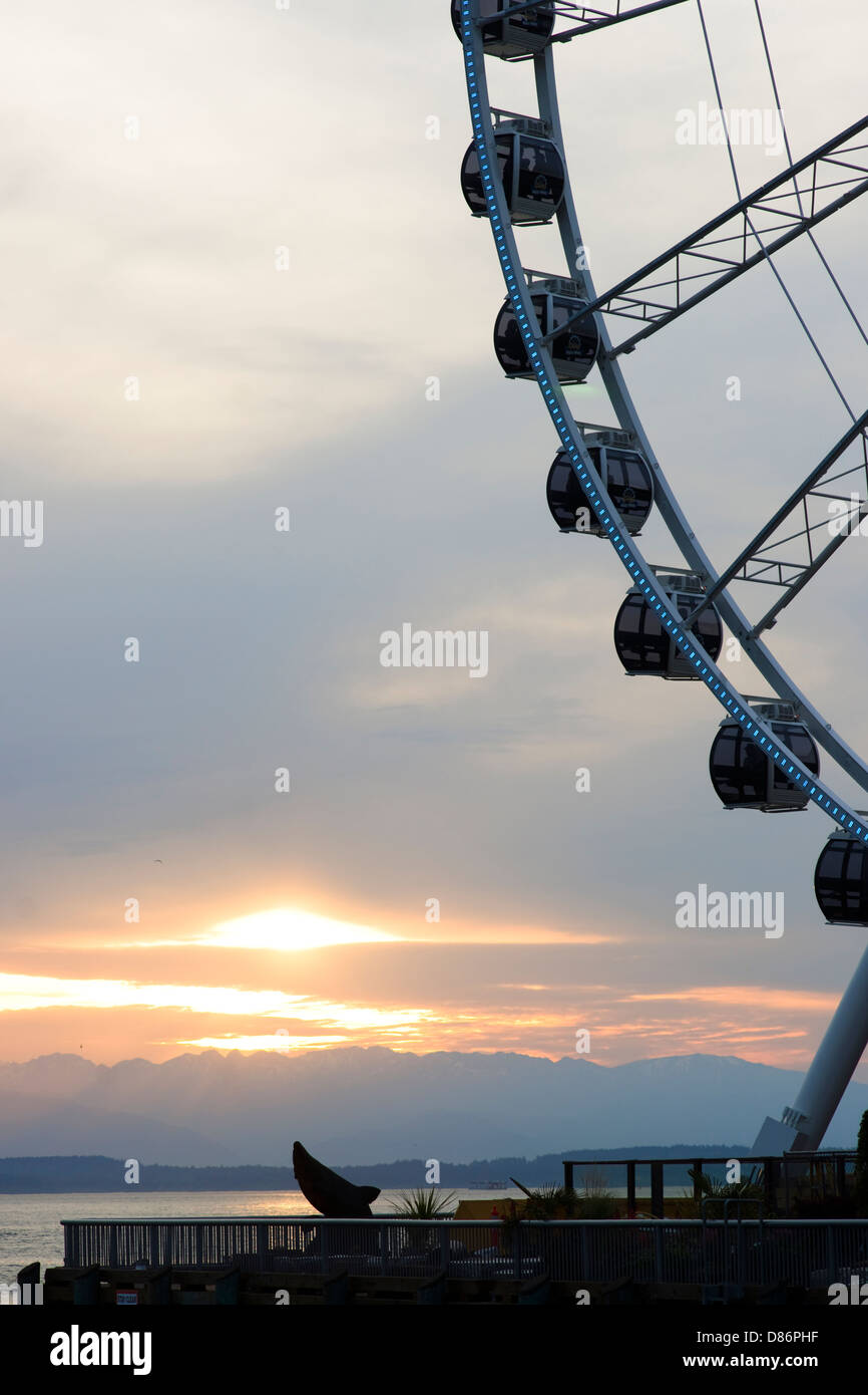 Tramonti dietro le montagne olimpiche e della Baia di Elliott con ruota panoramica Ferris in primo piano Foto Stock