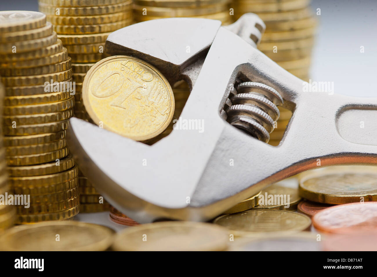 Pila di monete metalliche in euro e dieci cent trattenuto entro una chiave regolabile Foto Stock