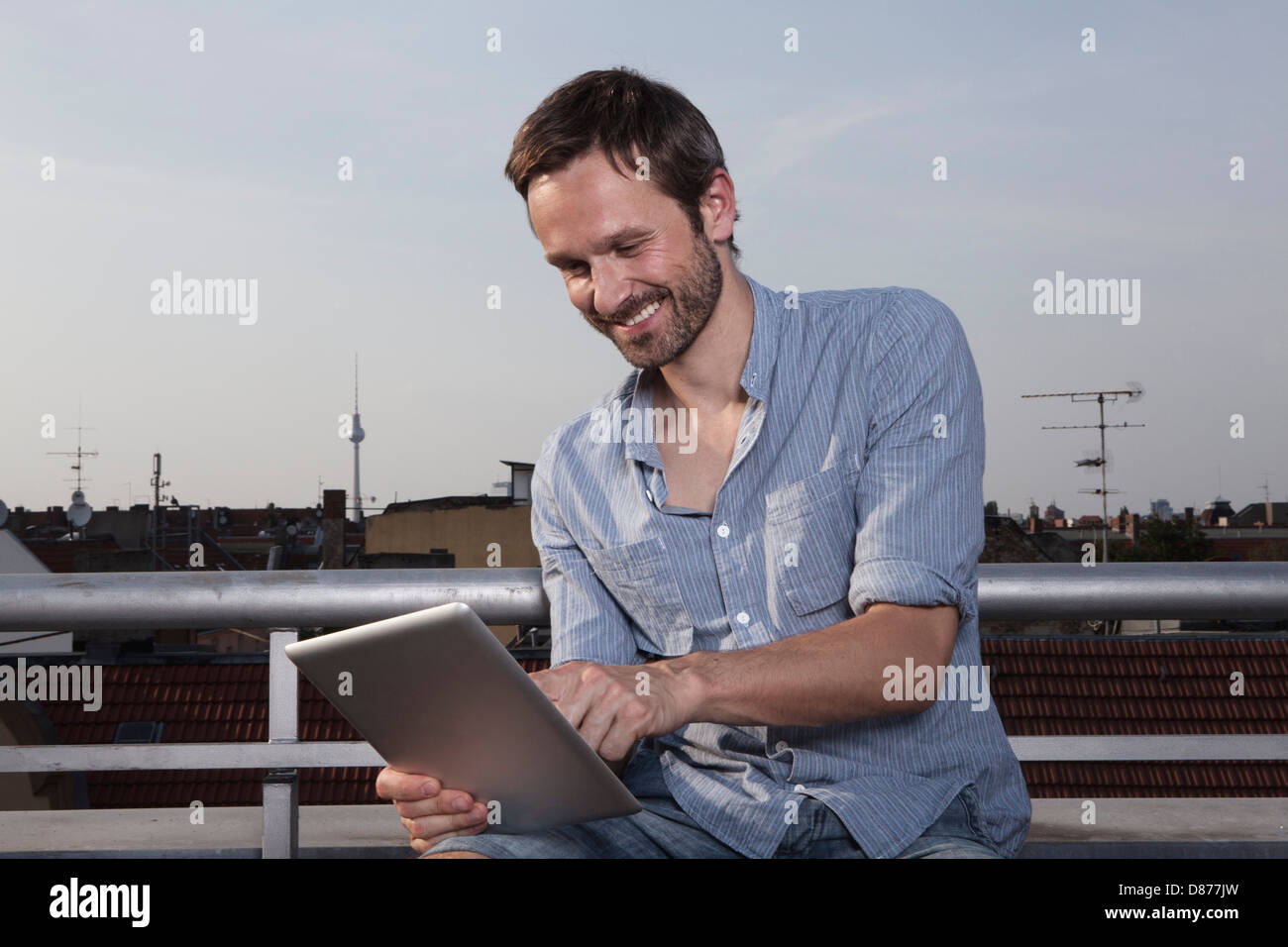 Germania, Berlino, uomo con tavoletta digitale sulla terrazza sul tetto, sorridente Foto Stock