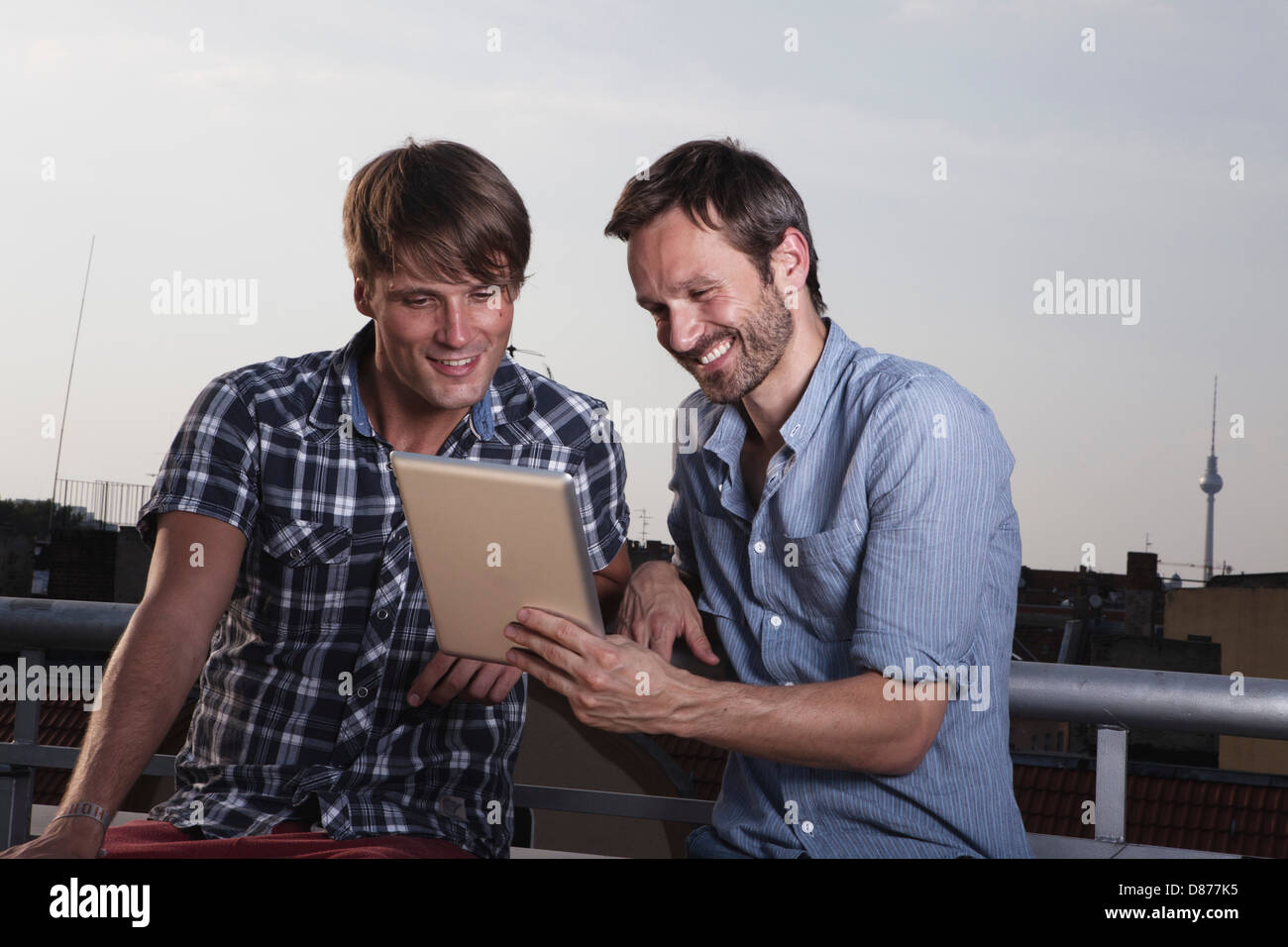 Germania, Berlino, uomini con tavoletta digitale sulla terrazza sul tetto, sorridente Foto Stock