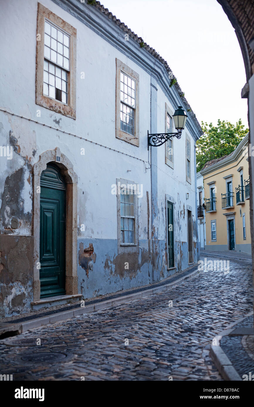 Case tradizionali lungo una strada di ciottoli all'interno del quartiere vecchio della città a Faro, Portogallo Foto Stock