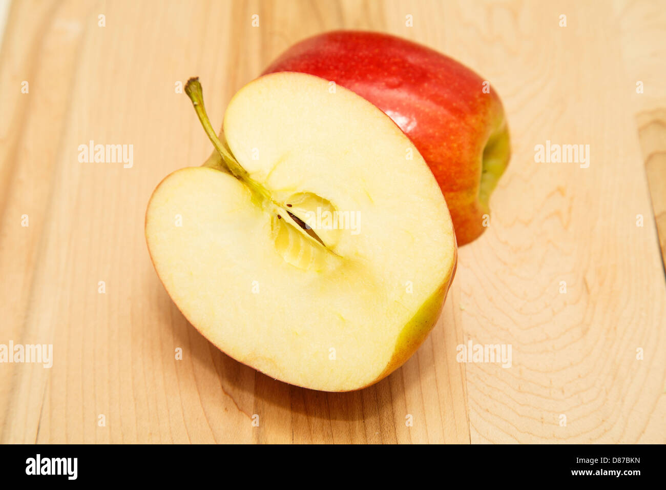 Fresche, mela rossa tagliata a metà su un legno tagliere Foto Stock