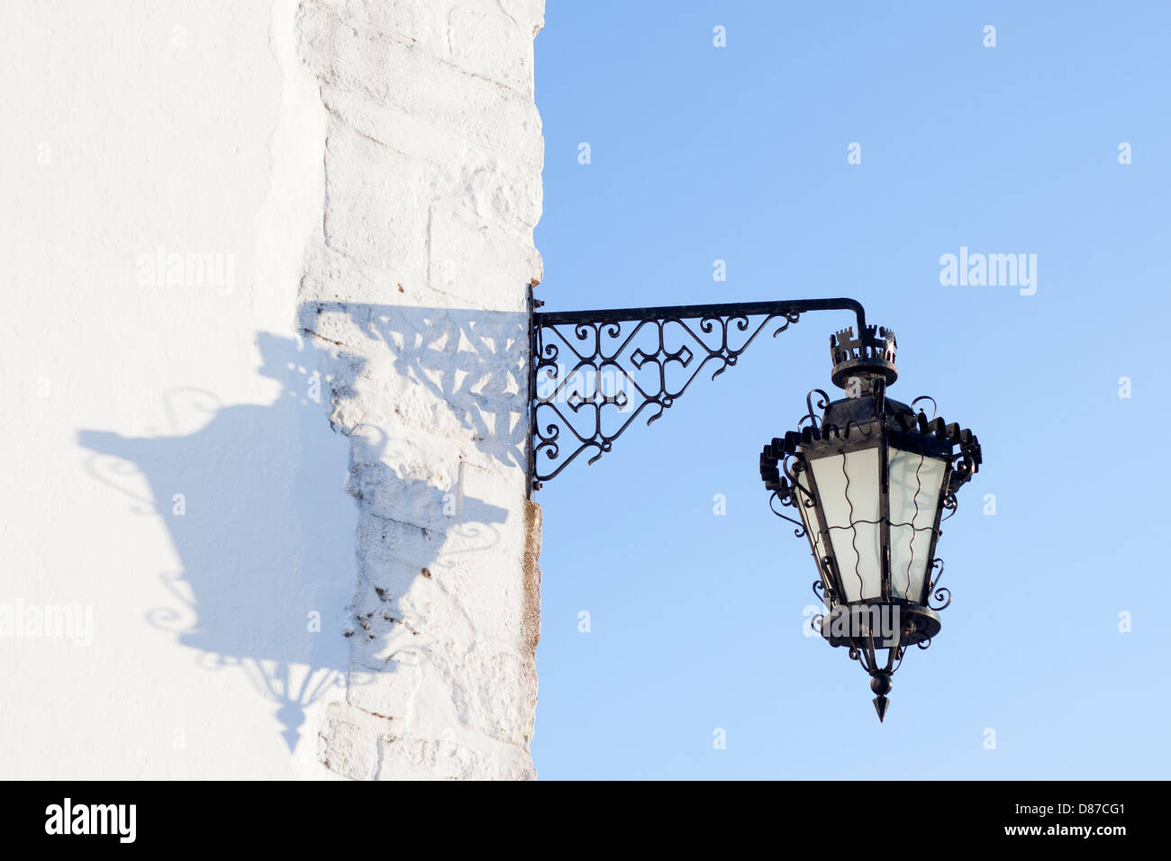 Ombra di un lampione su una parete bianca nella piazza del quartiere vecchio della città a Faro, Portogallo Foto Stock