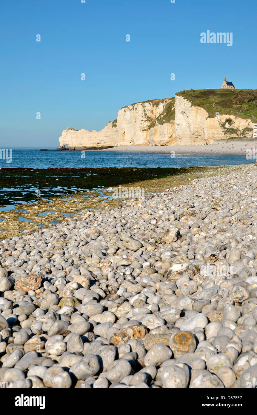 Spiaggia di ciottoli e la famosa scogliera a monte e la sua chiesa di Etretat, comune in Seine-Maritime dipartimento in Francia Foto Stock