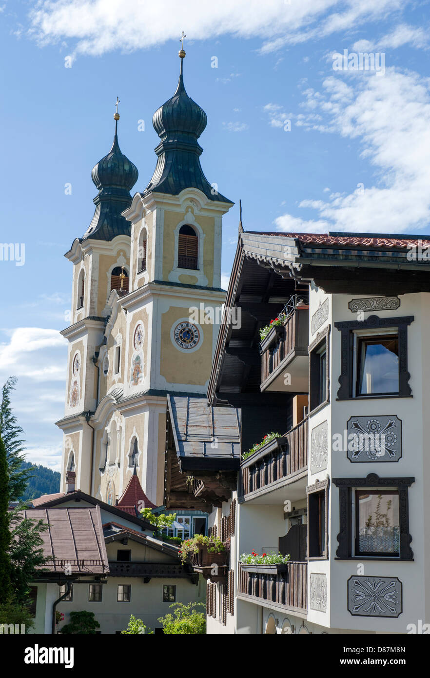 Chiesa parrocchiale di Hopfgarten e la facciata con decorazioni sgrafitti su un chalet di montagna in stile alpino in Tirolo, Austria Foto Stock