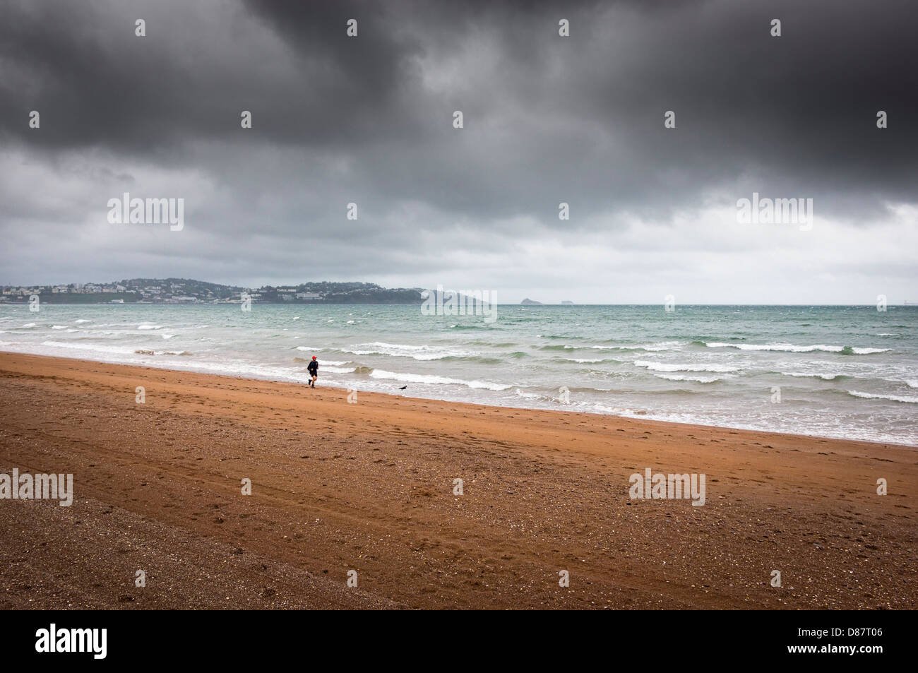 Runner in Paignton Beach sotto la pioggia con cielo tempestoso, Devon Coast, Inghilterra, Regno Unito nella primavera/estate Foto Stock