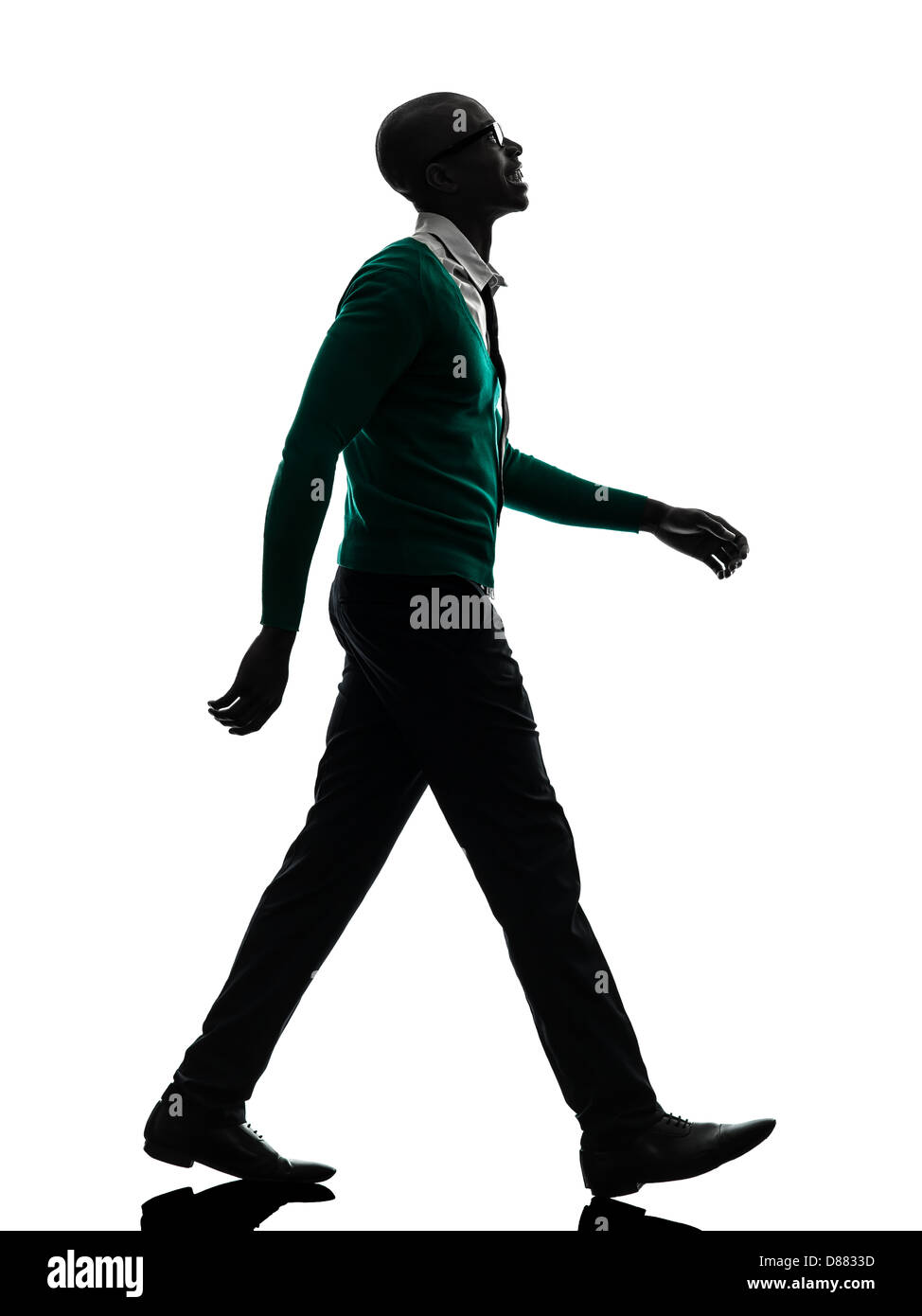 Uno nero africano uomo che cammina cercando sorridente in silhouette studio su sfondo bianco Foto Stock