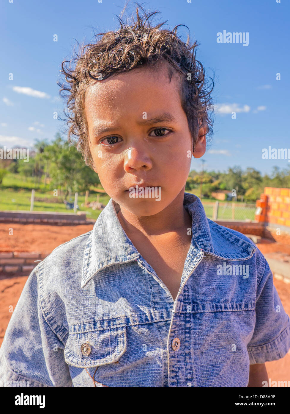 Un giovane ragazzo ispanico che indossa un blu jean camicia, ha molto chiara la pelle e sia rivolto in avanti con un aspetto strano in Luque, Paraguay. Foto Stock