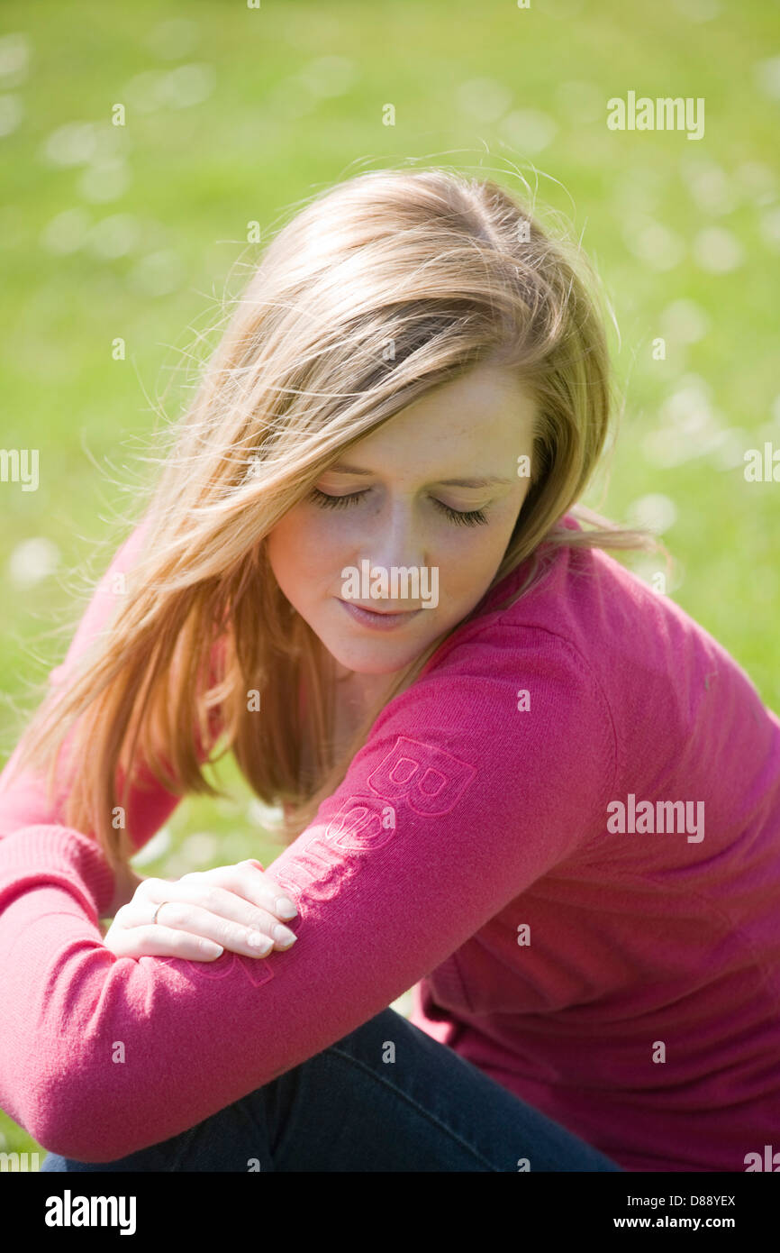 Bella bionda donna seduta al di fuori sul luminoso giorno. Foto Stock