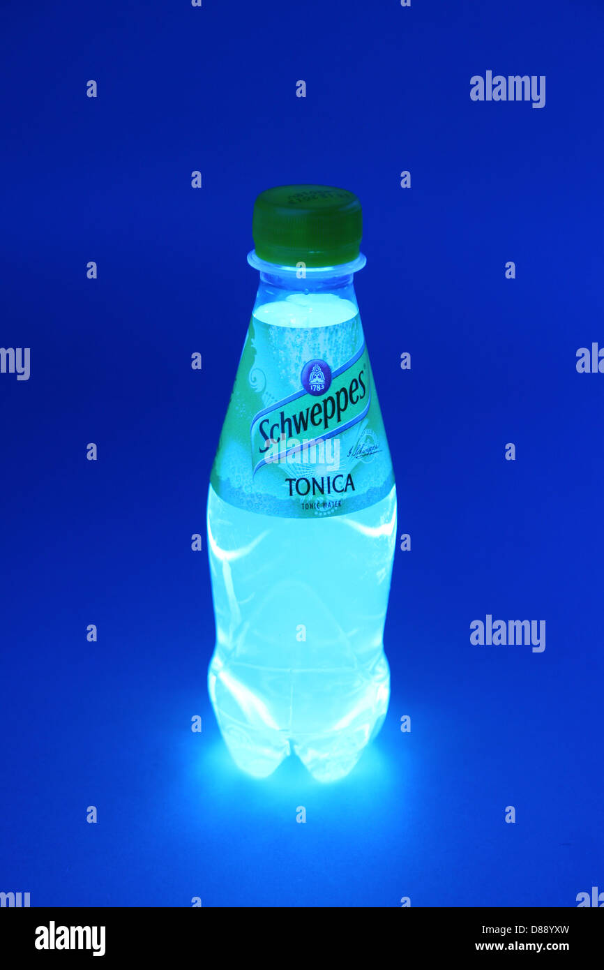 Marca piccola Schweppes tonica trasparente di acqua in bottiglia in raggi ultravioletti della luce UV è fluorescente. Foto Stock