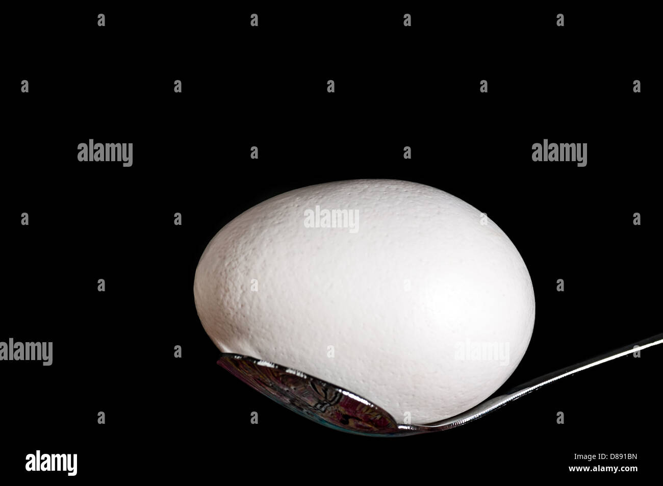 Le uova bianche,sul cucchiaio di metallo, anteriore accesa, isolata, sfondo nero, spazio di copia Foto Stock