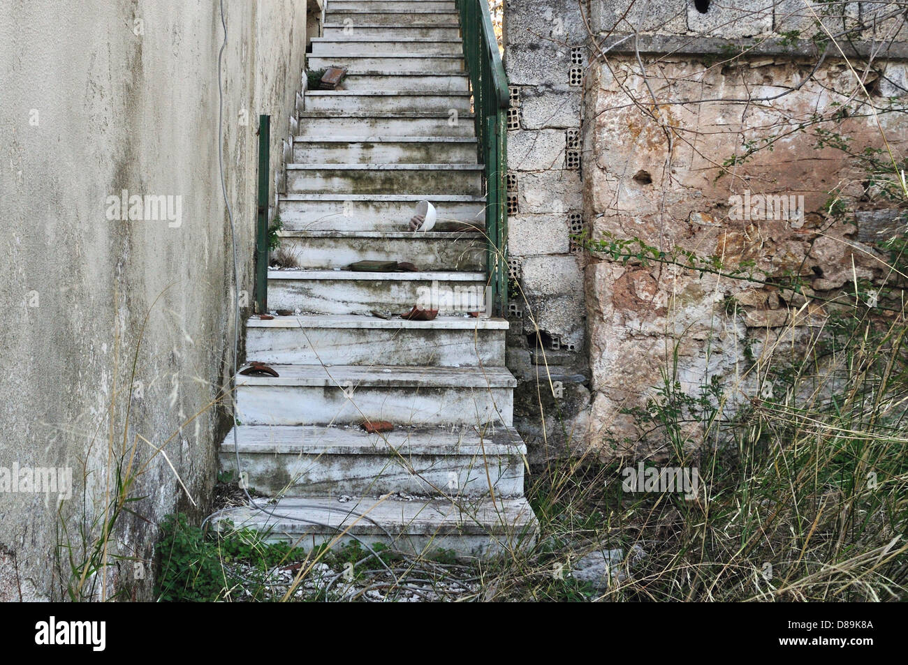 Casa abbandonata scalinata, sbriciolare parete e ricoperta di piante. Foto Stock
