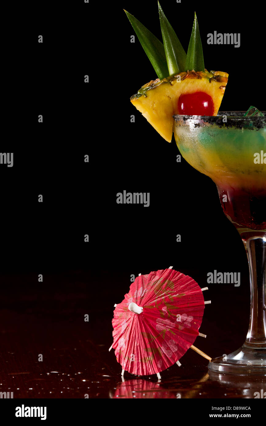 Bella tropical cocktail servito in un bicchiere Margarita con sale nero sul cerchio e una fetta di ananas con una ciliegia in esso Foto Stock