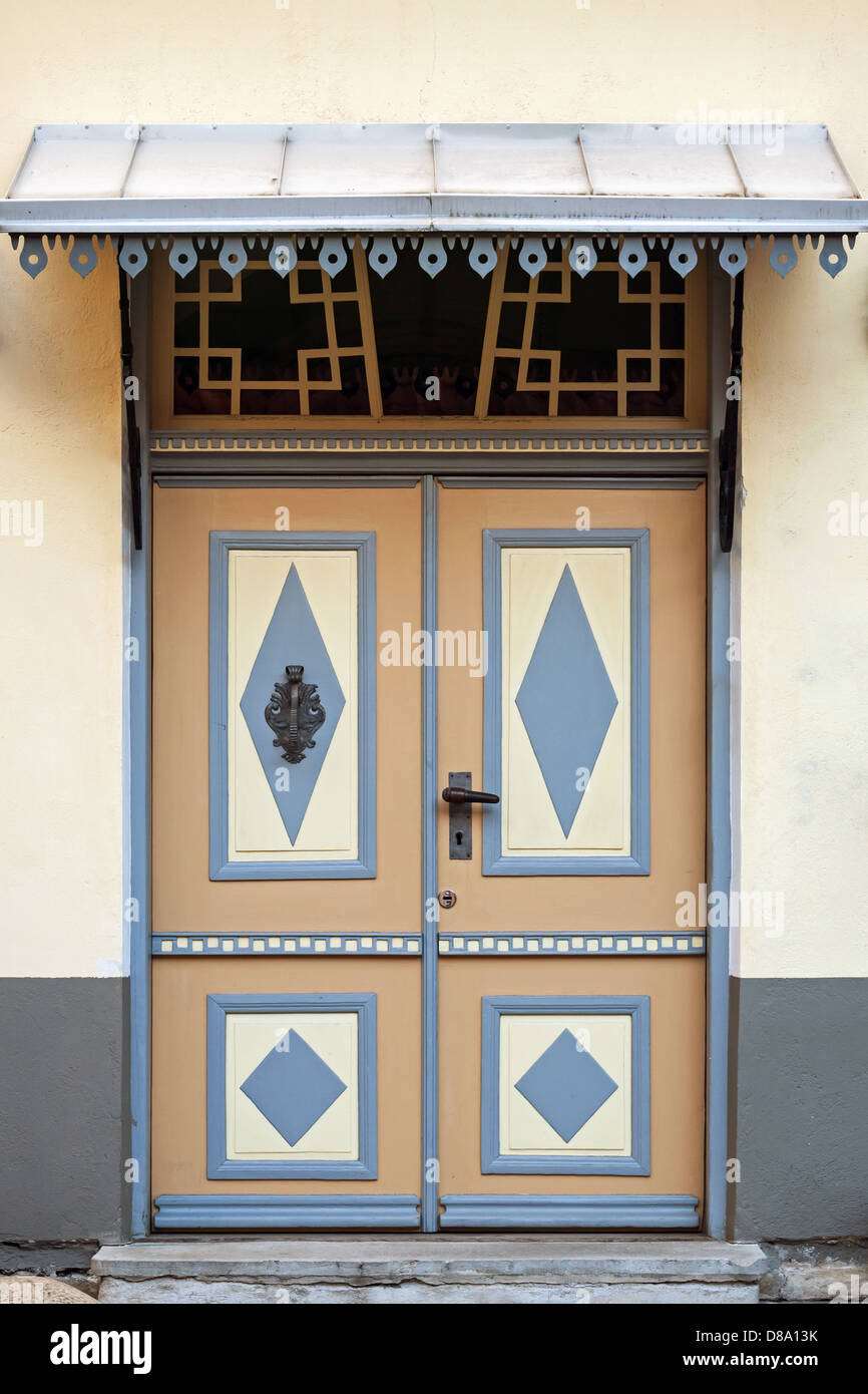 Giallo porta in legno con decorazione colorata e visiera nella vecchia facciata di edificio. Tallinn, Estonia Foto Stock
