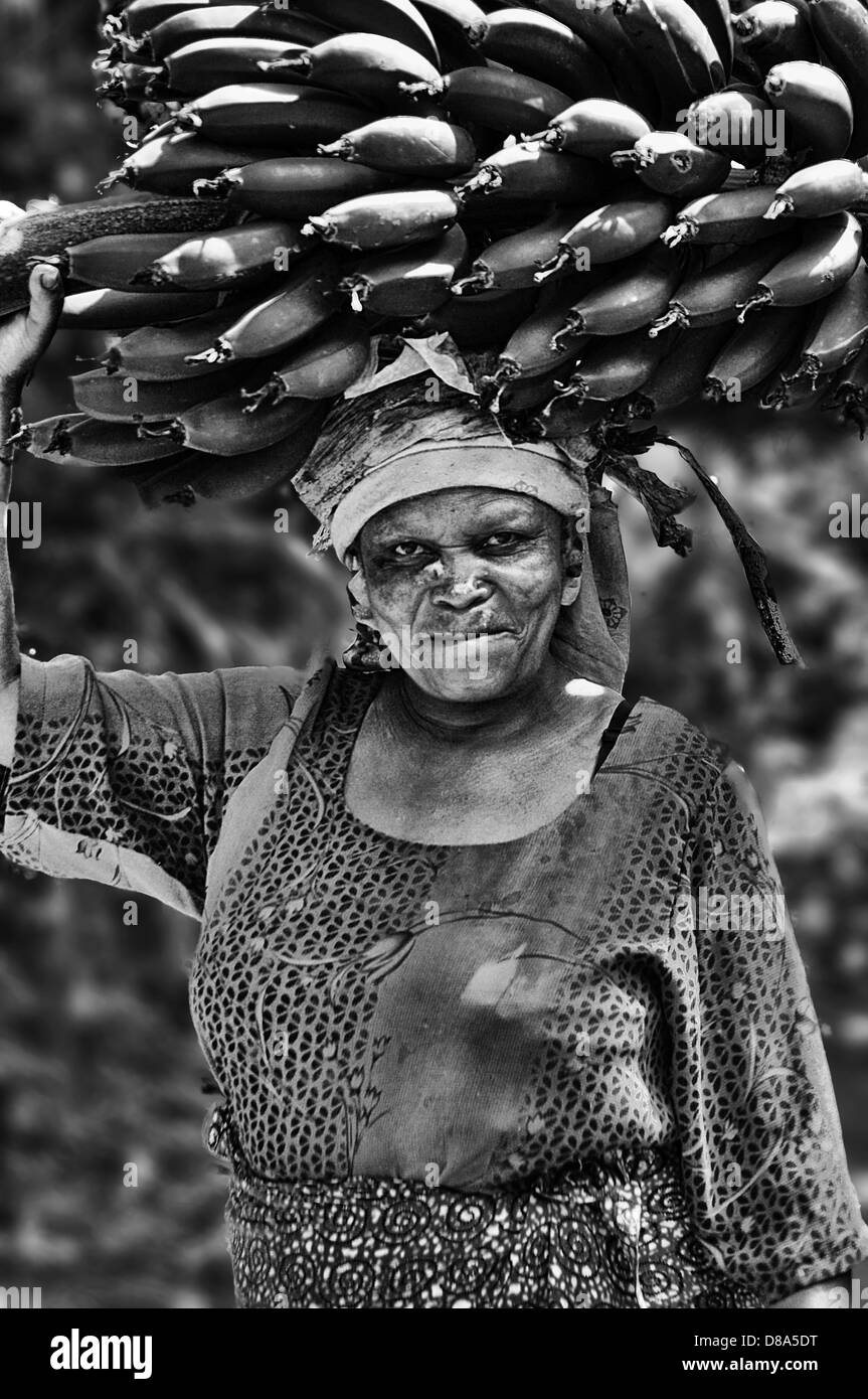 Una donna che porta Banana del cluster sulla sua testa, sulla strada per il mercato delle banane in alla Marangu village, Tanzania. Foto Stock
