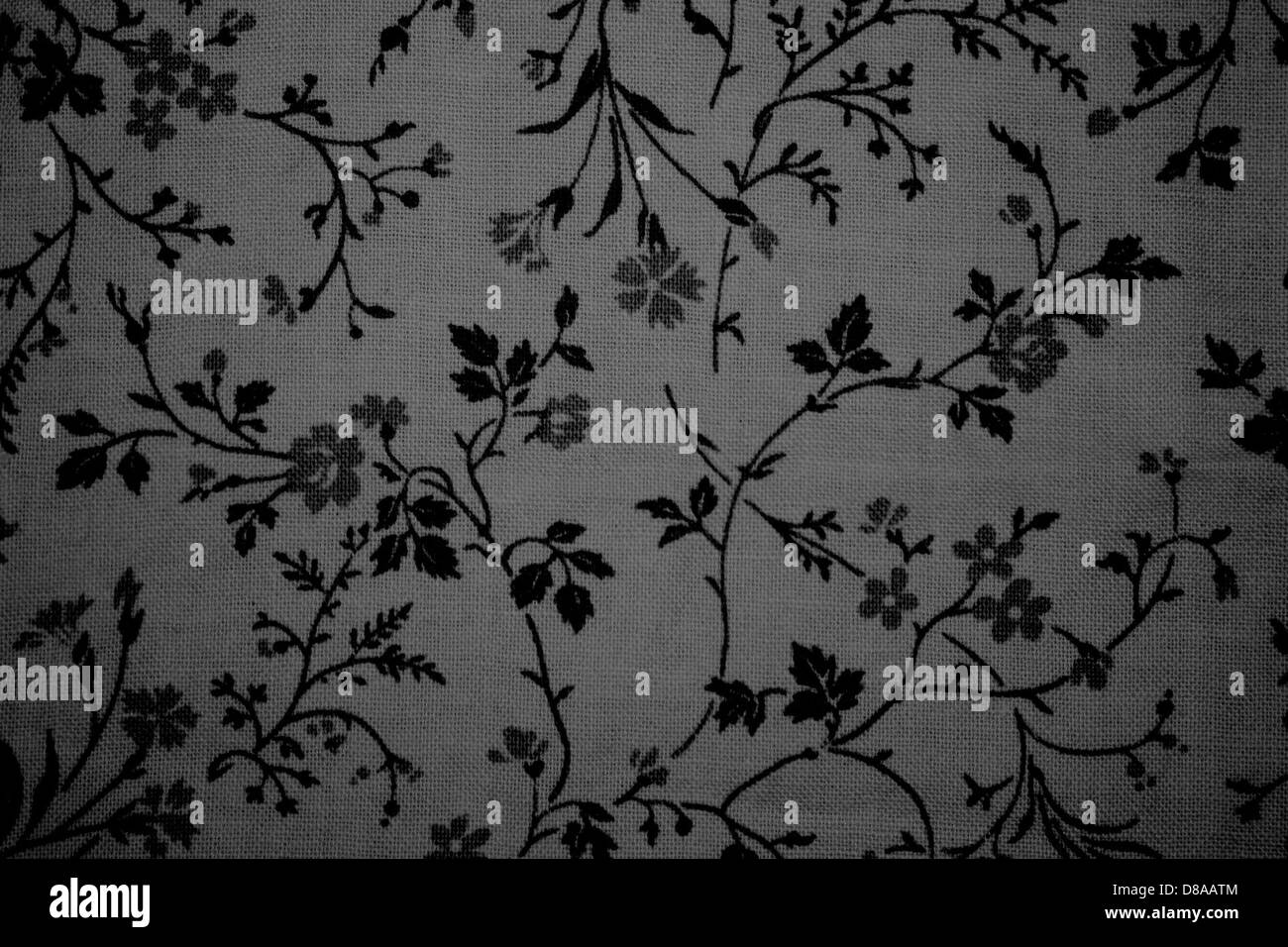 Vista ravvicinata di un tessuto con motivo floreale nero stampato su sfondo grigio. Il design è caratterizzato da intricati motivi floreali che si abbinano al delicato colore del tessuto. Foto Stock