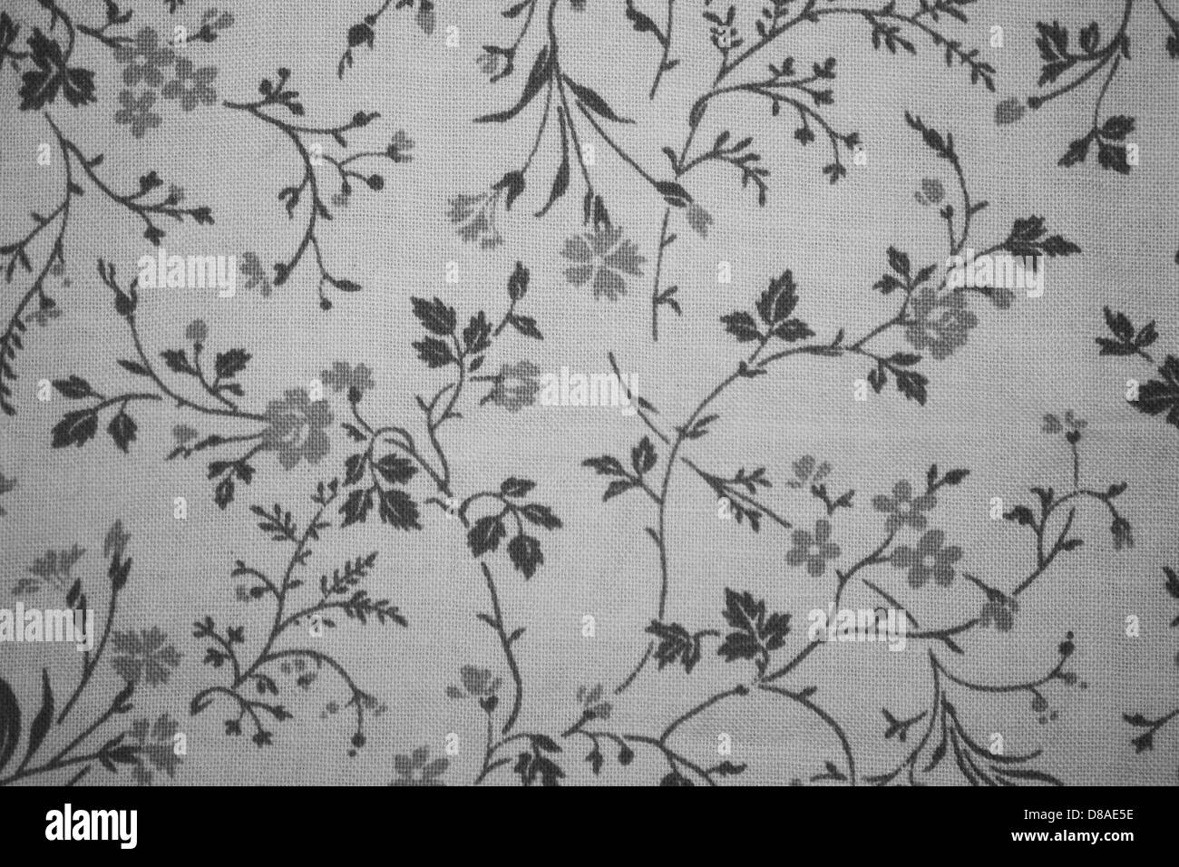 Questa immagine mostra un tessuto con una stampa floreale grigio su bianco, tipica dei tessuti per l'abbigliamento o l'arredamento della casa. L'intricato motivo floreale crea un aspetto delicato ed elegante. Foto Stock