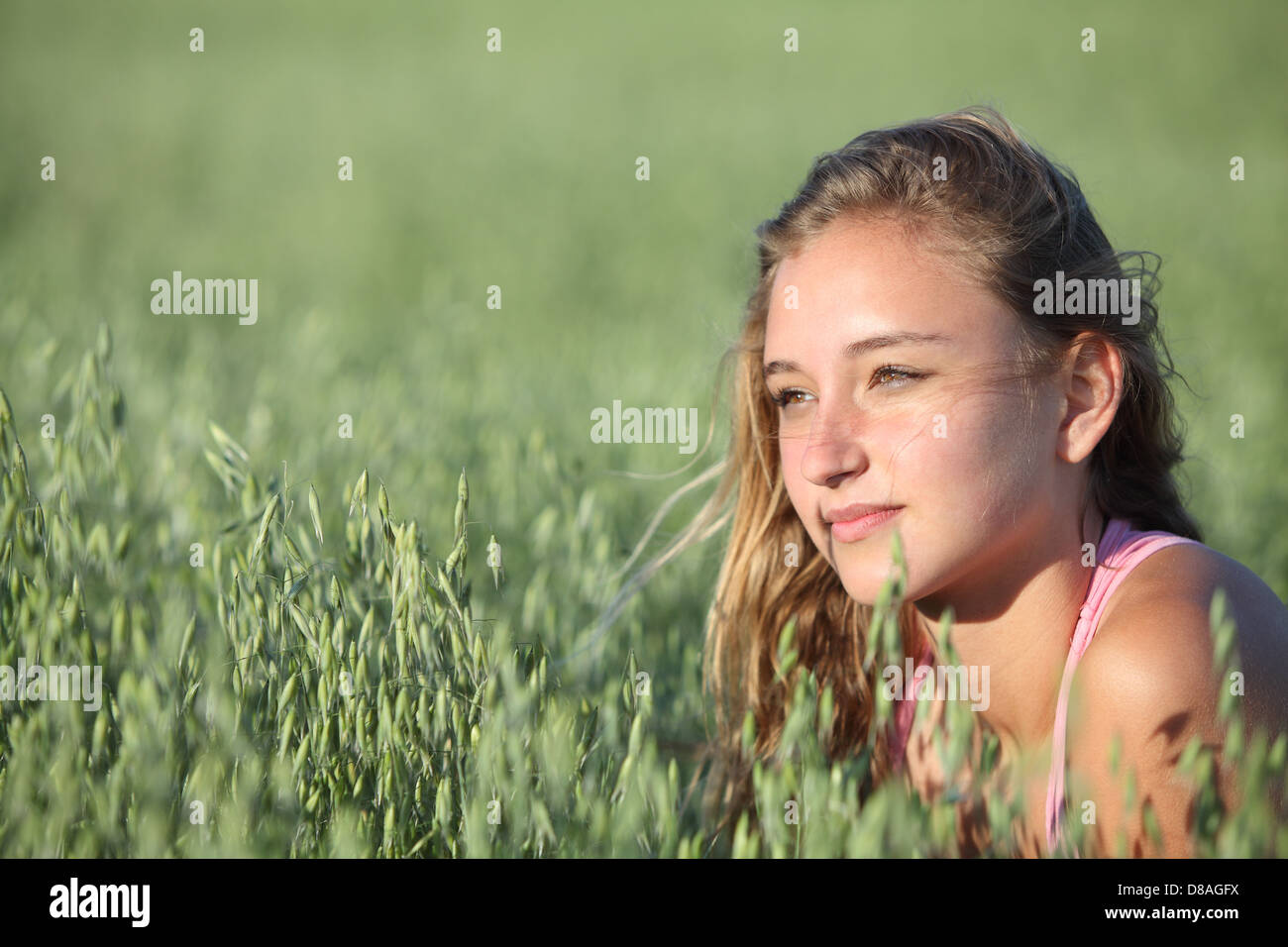 Ritratto di una bella ragazza adolescente faccia in un unfocused verde prato di avena Foto Stock