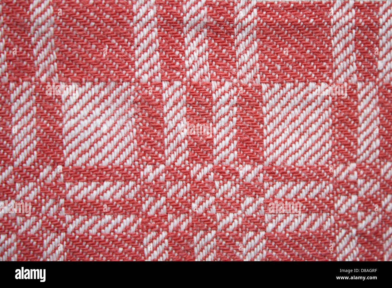 Un primo piano di un tessuto intrecciato rosso e bianco, con un motivo quadrato. La texture e il motivo del tessuto conferiscono un look dinamico, perfetto per il design tessile o i materiali alla moda. Foto Stock
