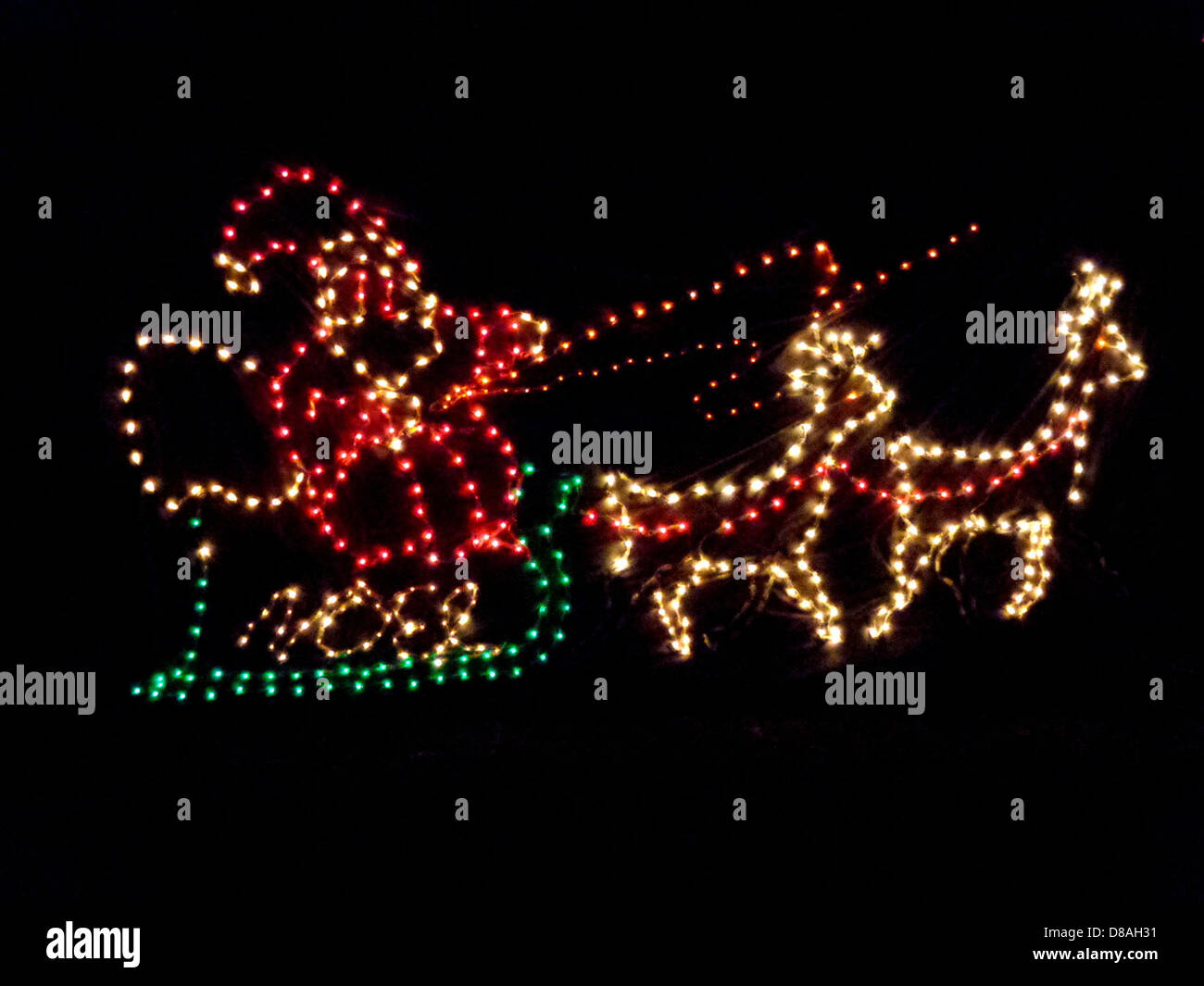 Un'esibizione festosa della slitta di Babbo Natale decorata con luci natalizie, catturata durante le festività natalizie. Le luci conferiscono alla slitta un aspetto vivace e colorato, che si aggiunge all'allegria natalizia. Foto Stock