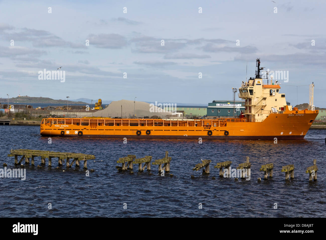 Una grande nave arancione al porto di Leith vicino a Edimburgo in Scozia con un tumulo a destra dietro la nave Foto Stock