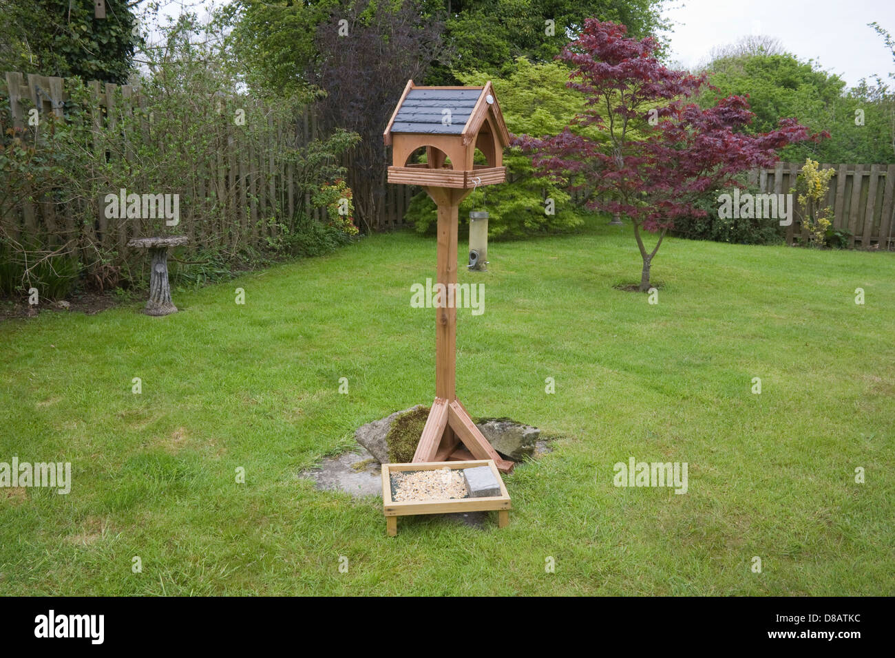 Regno Unito Tabella di uccelli e alimentatori su un giardino prato Foto Stock