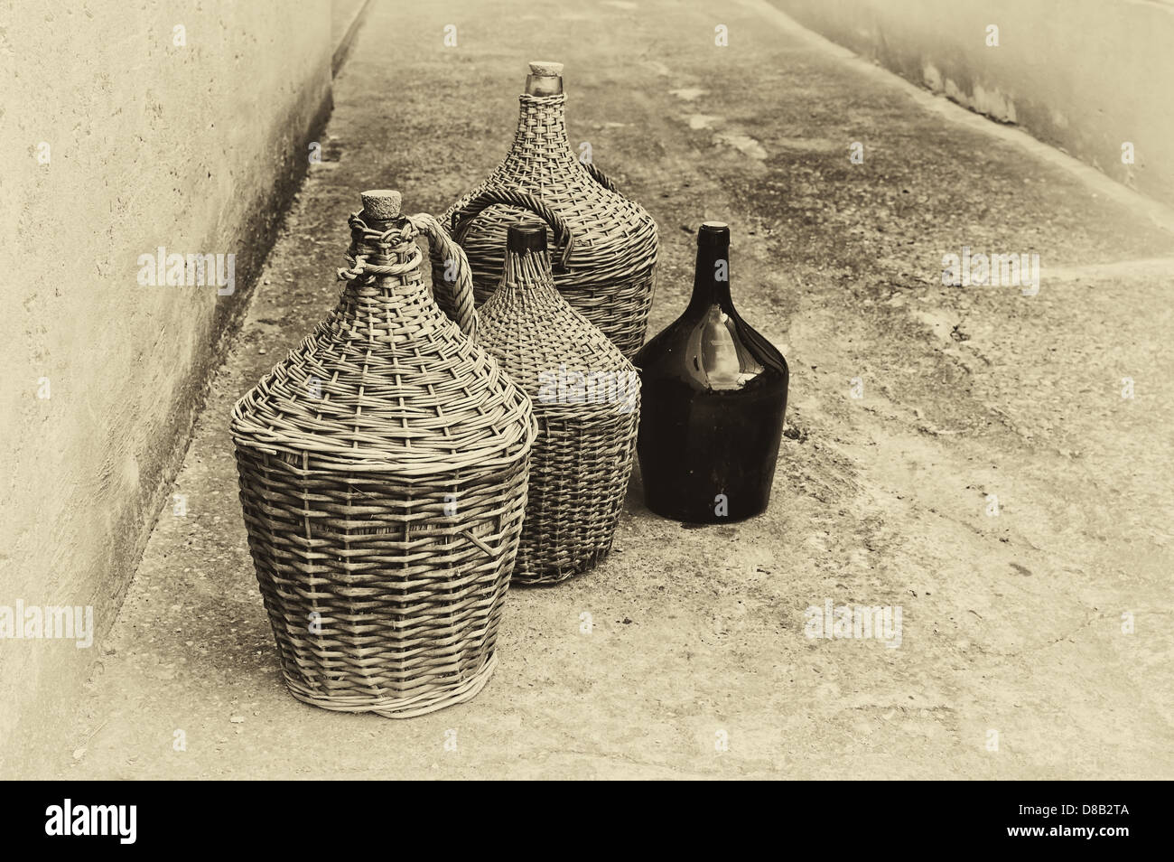 Tessuto di vimini e bottiglie di vino. Immagine in bianco e nero stilizzata come cartolina vintage. Foto Stock