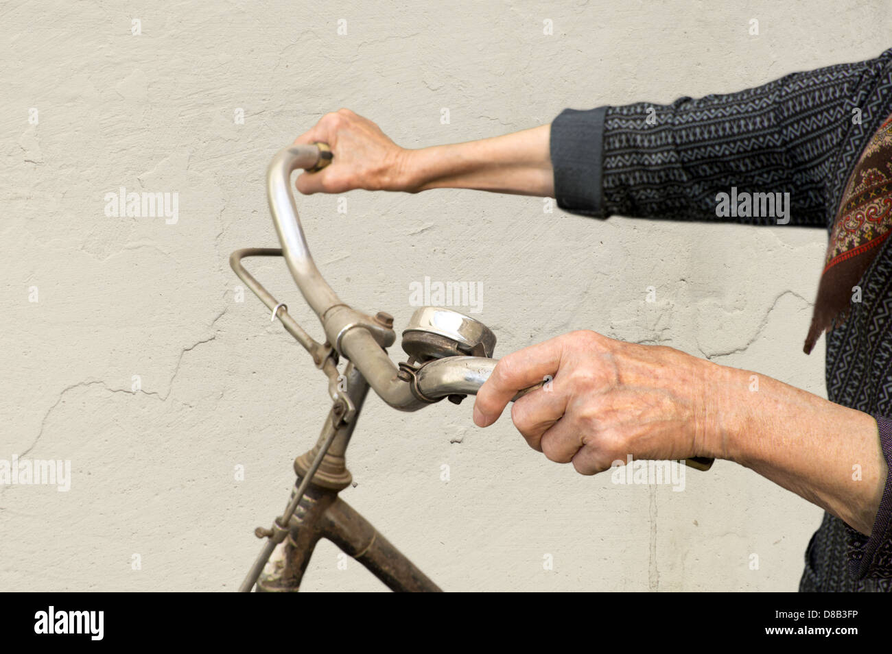 Vecchio mani tenendo il manubrio di una bicicletta. Foto Stock
