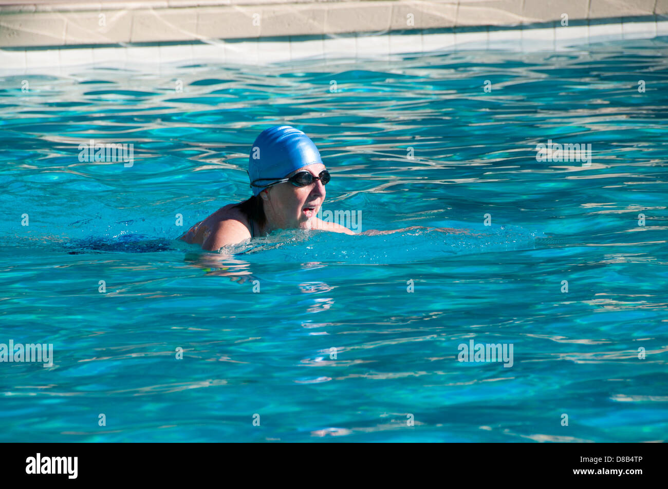Donna giri di nuoto in piscina Foto Stock