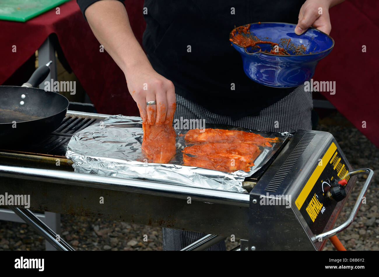 L'uomo ponendo i filetti di trota rivestita in salsa tandoori su un barbecue. Foto Stock